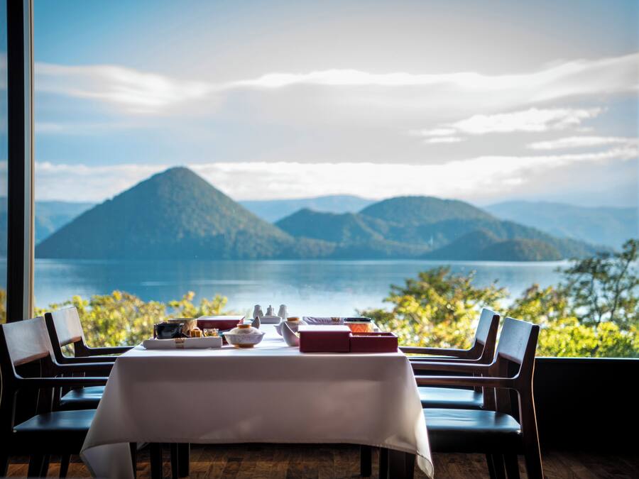 A dining table with a view of a mountainous landscape through large windows.