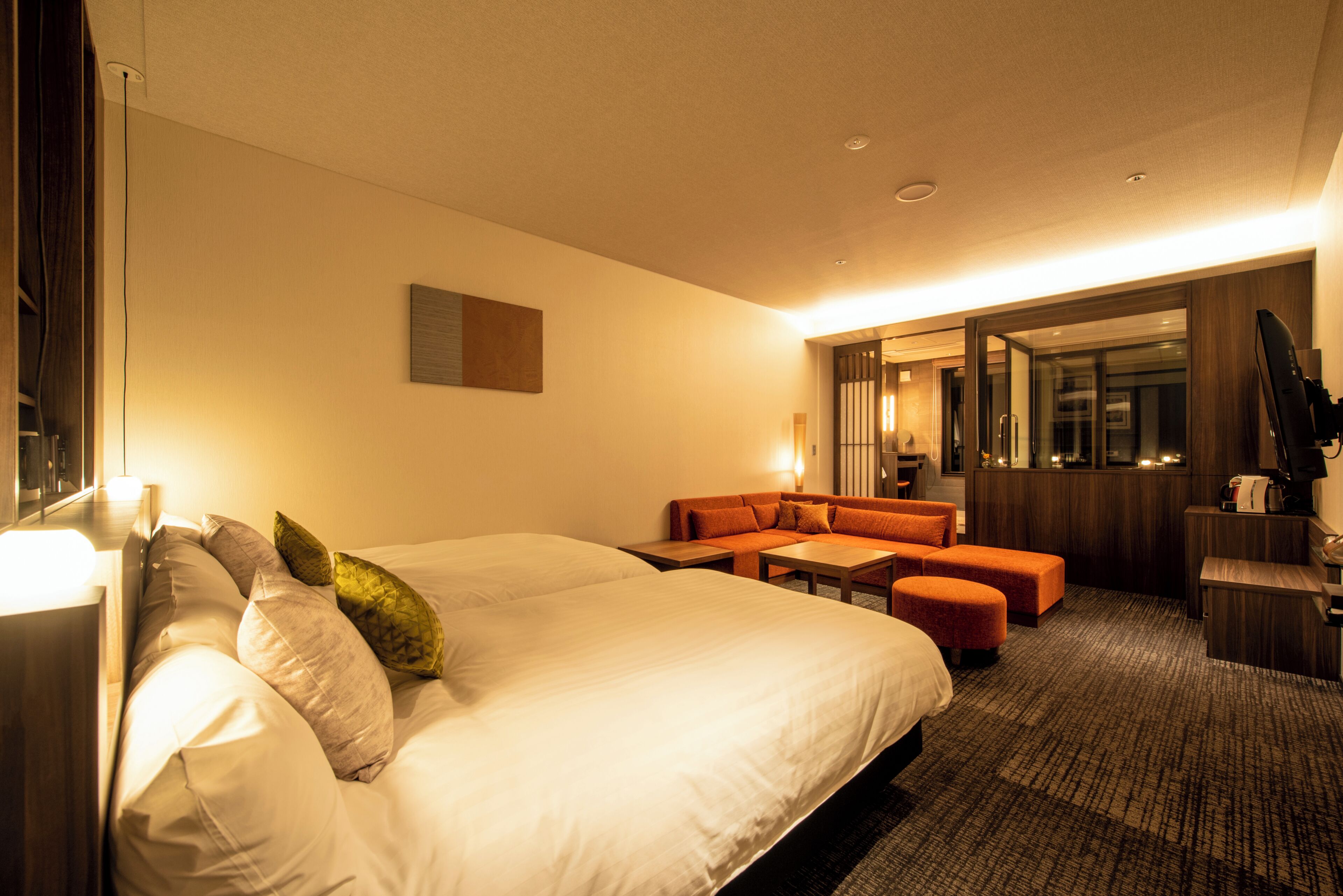 A hotel room with a large bed, a sofa, a small table, and a mirror.