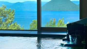 Una habitación con un gran ventanal con vistas a un cuerpo de agua y una montaña.
