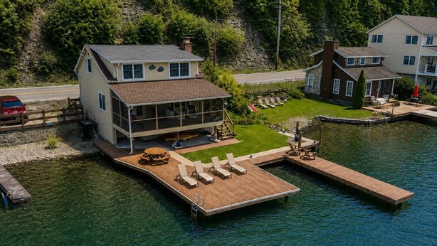 Ein Seegrundstück mit Steg, einer überdachten Terrasse und Blick auf das Wasser.