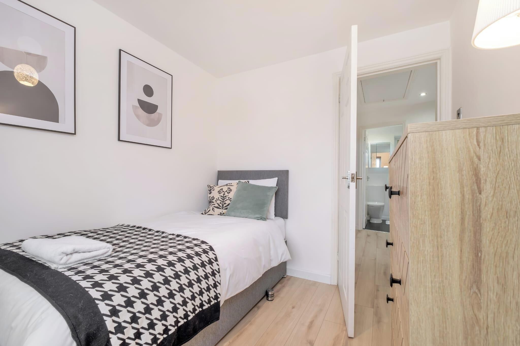 Une chambre à coucher comprenant un lit, une armoire et deux œuvres d’art encadrées accrochées au mur.