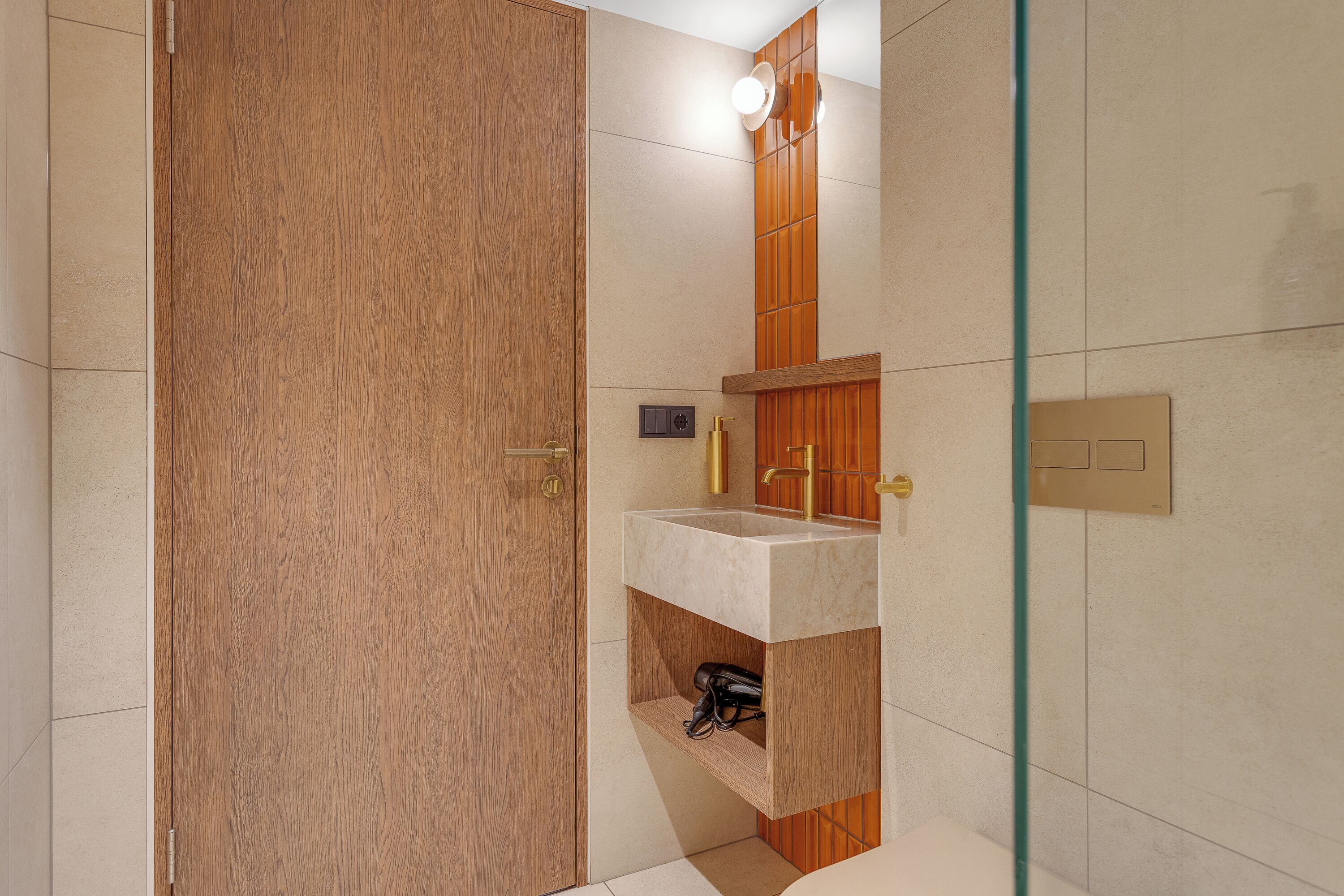 A bathroom with a wooden door, a sink with a mirror, and a shower area.