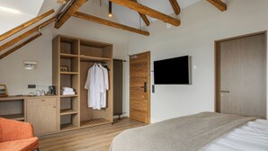 A bedroom with a bed, a TV, a wooden wardrobe, and a chair. - Bryggjan Boutique Hotel (Akureyri)