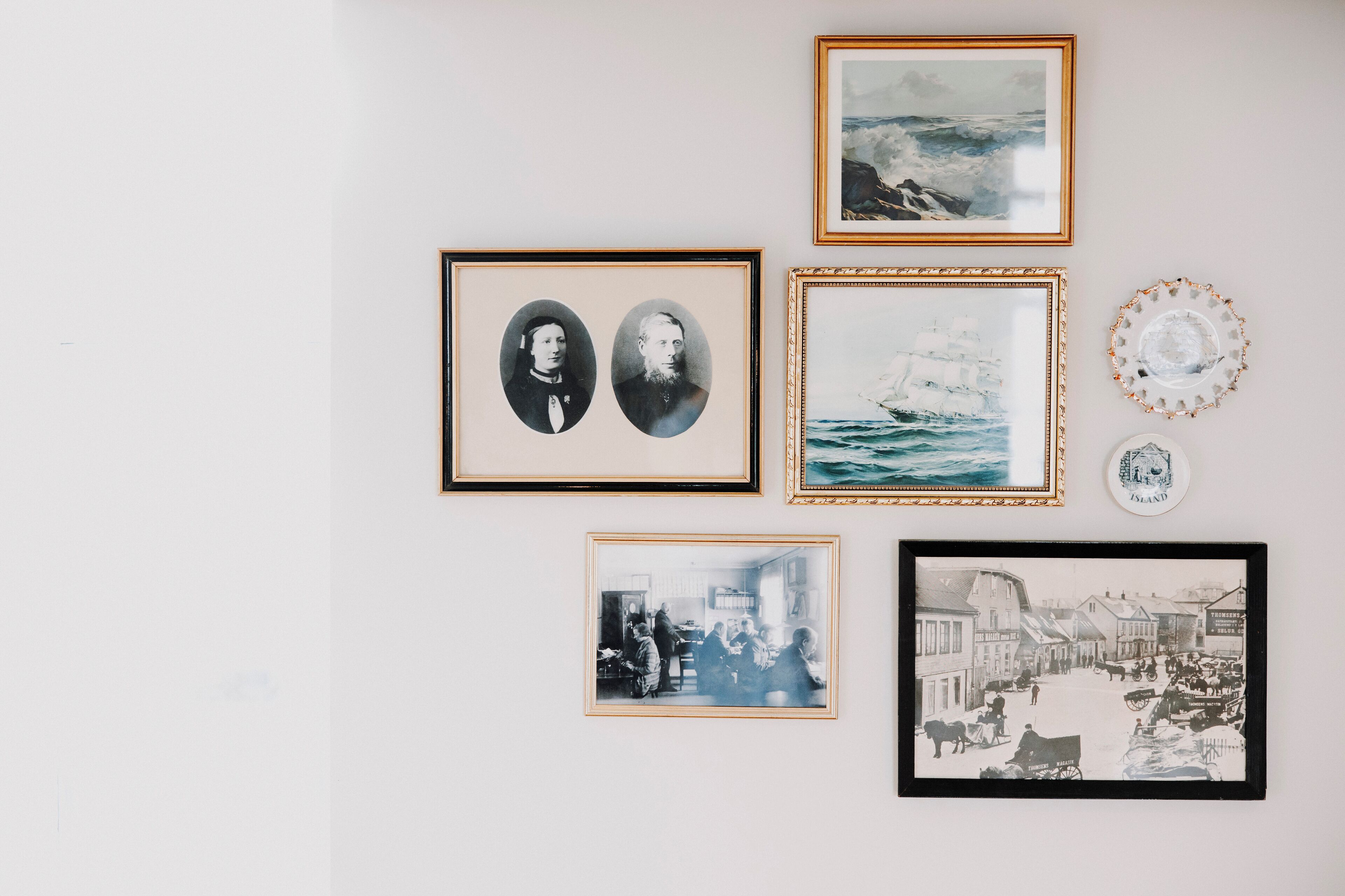Una pared con varias fotografías enmarcadas y objetos decorativos.
