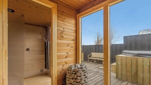 A wooden interior with a sauna, a wooden bench, and a view of the outside. - Bryggjan Boutique Hotel (Akureyri)