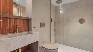 Un baño moderno con lavamanos de mármol, inodoro y ducha.