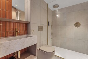 Un baño moderno con lavamanos de mármol, inodoro y ducha.