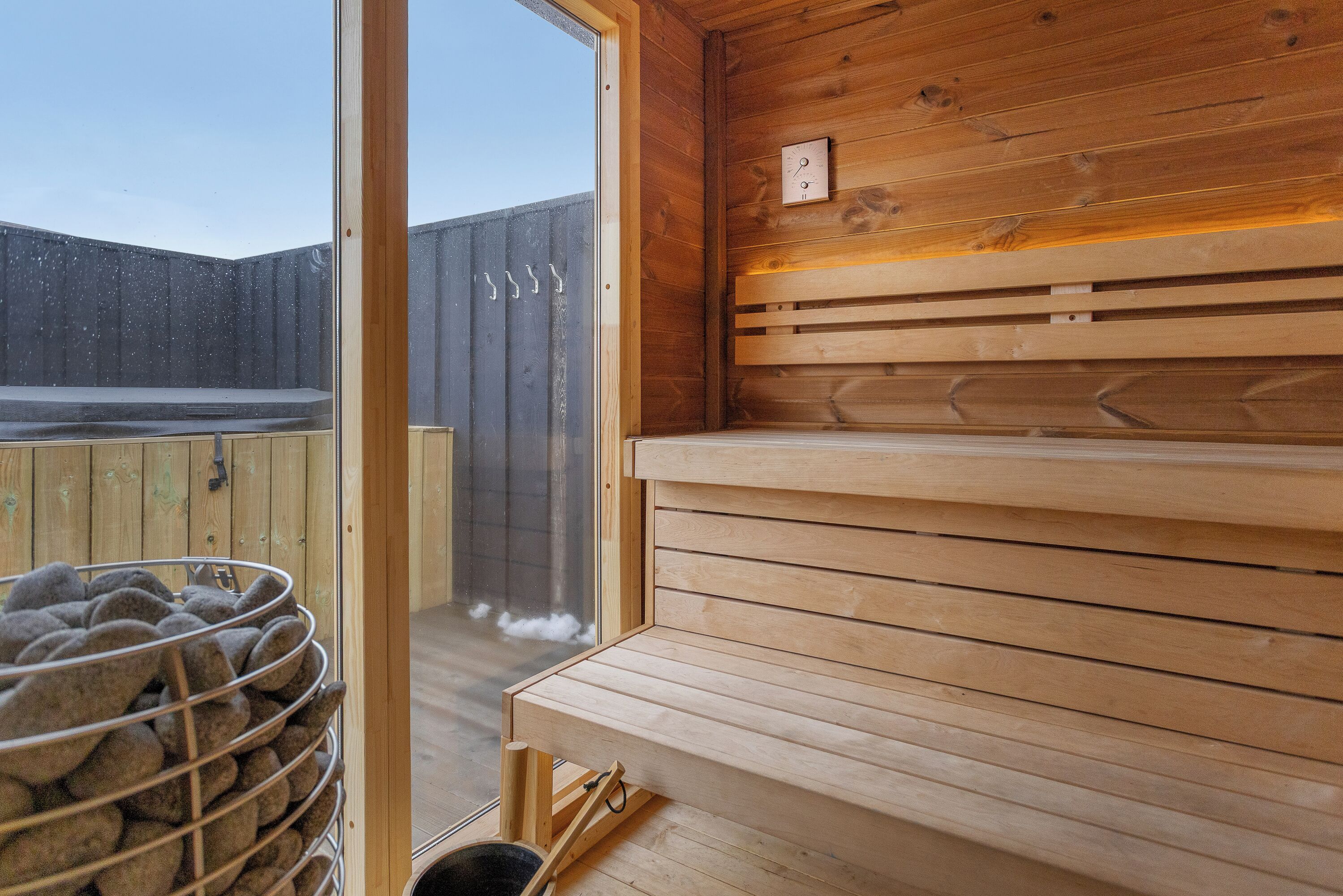 A sauna with wooden benches and a metal rack of towels.