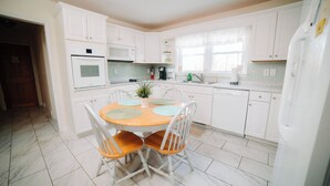 A kitchen with white cabinets, a round table with chairs, and a refrigerator. - Relax at this serene waterfront retreat featuring a private dock, perfect for lake lovers! (Dublin)