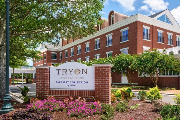 A brick building with a sign that reads "TRYON Riverfront Inn Tarryry Collection by Hilton."