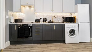 Una cocina moderna con gabinetes grises, horno empotrado, lavadora y microondas.