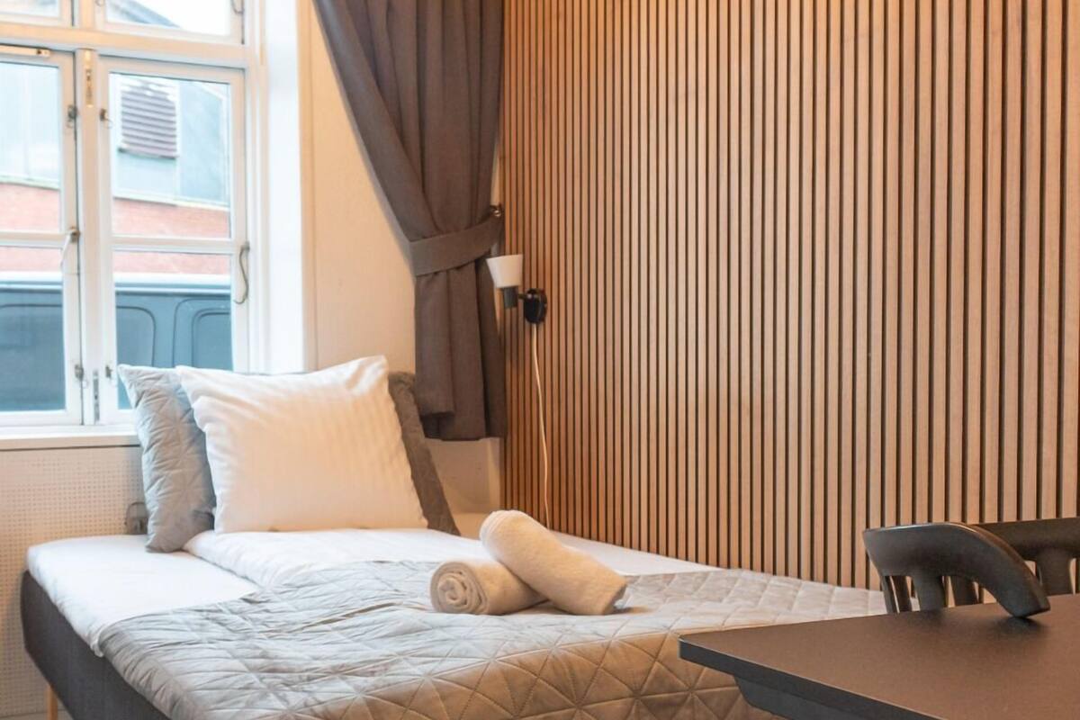 Una habitación de hotel con una cama, un escritorio y un ventanal con cortinas.
