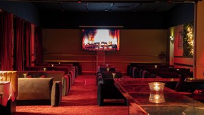 A theater with rows of red velvet seats, a large screen, and a red carpeted floor. - Hotel Assens (Assens)