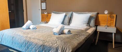 A hotel room with a large bed, two bedside tables, and a door.