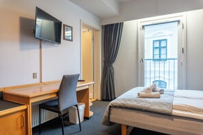 Work and unwind in comfort with a desk, chair, and flat-screen TV, plus a cozy bed with a quilted cover.