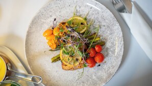 A plate with grilled fish, cherry tomatoes, asparagus, and lemon slices. - Hotel Assens (Assens)