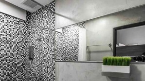 Ein modernes Badezimmer mit Schachbrettboden, Toilette, Bidet und einem Spiegel mit einer Zimmerpflanze.