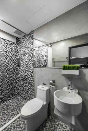 A modern bathroom with a checkered floor, a toilet, a bidet, and a mirror with a green plant. - At Home Hotel Zhongshan (Taipei)