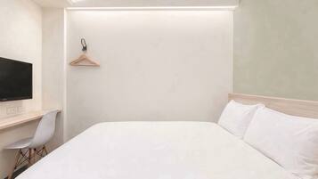 Une chambre d’hôtel équipée d’un lit, d’un bureau, d’une chaise et d’un téléviseur.