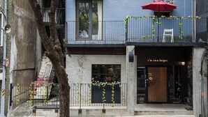 A building with a blue facade, graffiti art, and a red umbrella outside a shop named "i'm inn taipei". - At Home Hotel Zhongshan (Taipei)
