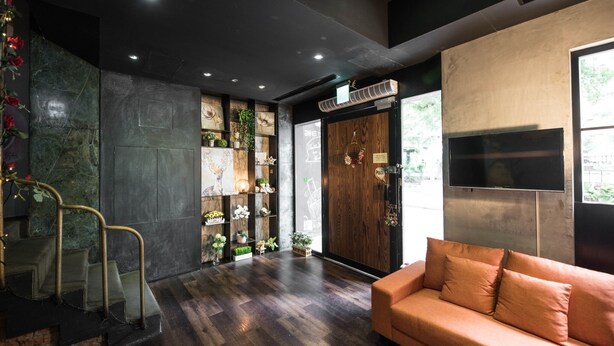 A modern interior with a dark wooden floor, a sofa, a TV mounted on the wall, and a wooden door with a 'PULL' sign. - At Home Hotel Zhongshan (Taipei)
