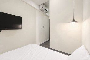 A modern hotel room with a flat-screen TV mounted on the wall, a hanging pendant light, and a neatly made bed. - At Home Hotel Zhongshan (Taipei)
