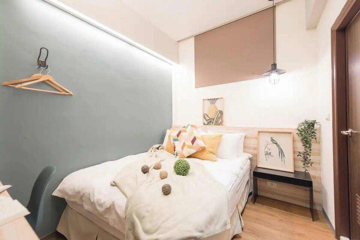 A neatly arranged bedroom with a bed, bedside table, and a hanging light fixture.