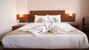 Une chambre d’hôtel avec un lit, deux tables de chevet et des lampes fixées au mur.