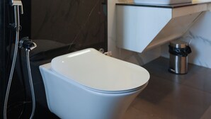 Une salle de bain moderne avec des toilettes blanches, un lavabo et une douche.
