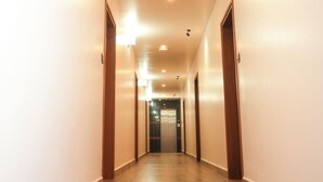 Un long couloir étroit, doté d’un plancher en bois et de murs blancs.