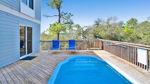 A wooden deck with a swimming pool, a covered patio area, and a view of trees and a building. - Sleeps 16 · Private Pool · 3 Blocks to Beach (Gulf Shores)