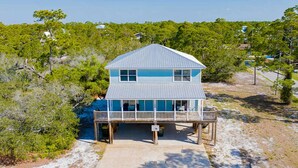 A two-story beachfront house with a balcony, surrounded by trees and a clear sky. - Sleeps 16 · Private Pool · 3 Blocks to Beach (Gulf Shores)