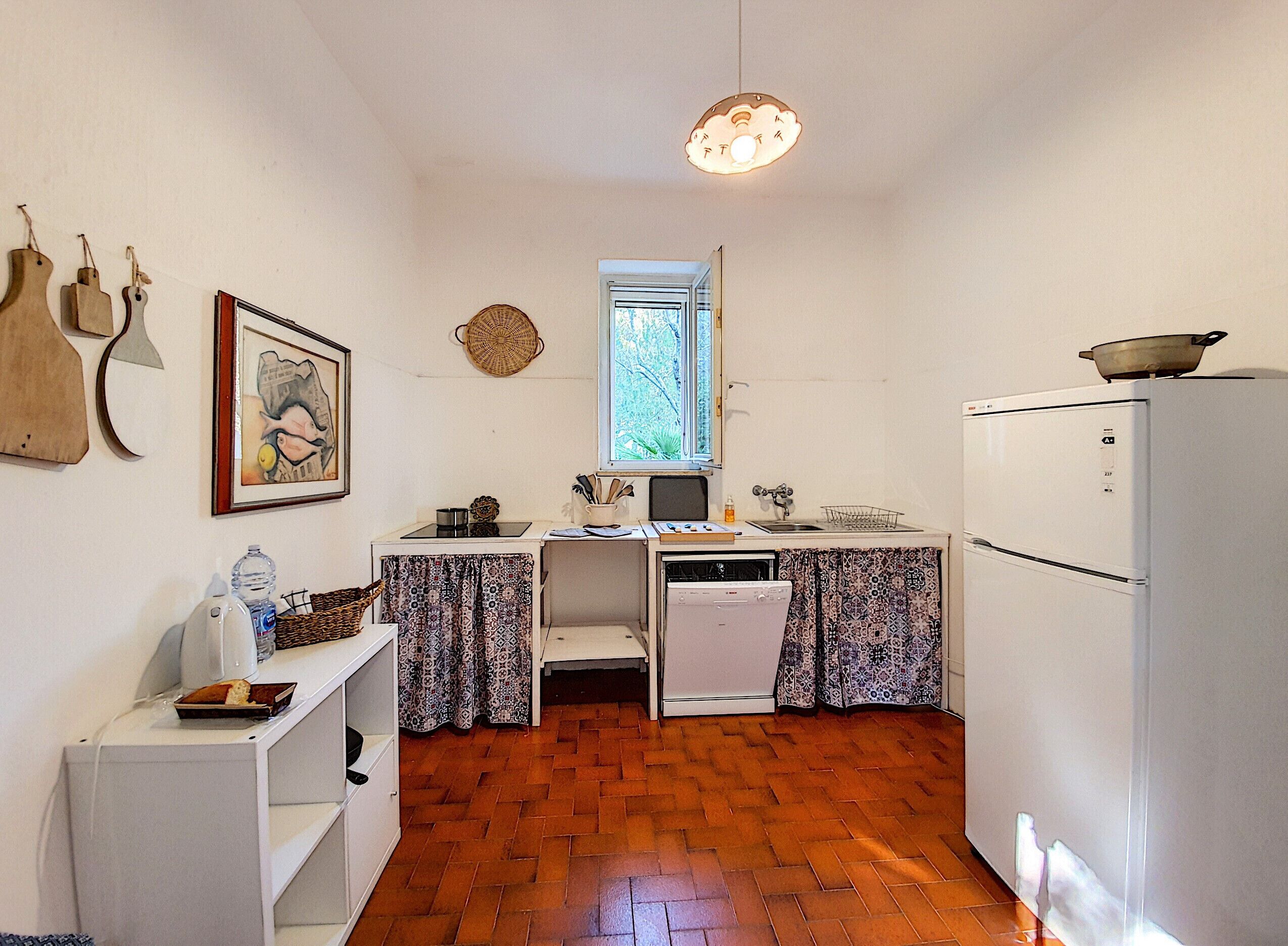 A compact kitchen with a white refrigerator, a small sink, and a window.