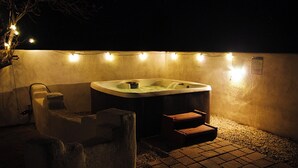 A hot tub with steps, a stone bench, and a wall with string lights. - Beautiful and fun 5 bedroom house with a hot tub, arcade games and lots of room. (Albuquerque)