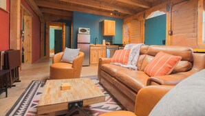 A cozy log cabin interior with a living room, a kitchen, and a dining area. - Beautiful and fun 5 bedroom house with a hot tub, arcade games and lots of room. (Albuquerque)