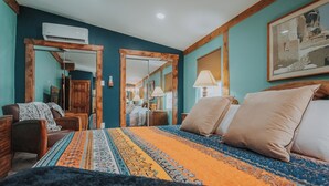 A bedroom with a large bed, a wooden wardrobe, a desk, and a chair. There is a mirror, a lamp, and a framed picture on the wall. - Beautiful and fun 5 bedroom house with a hot tub, arcade games and lots of room. (Albuquerque)