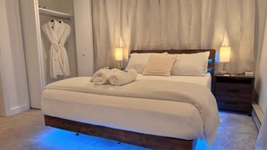 A neatly made bed with a wooden headboard, two bedside lamps, and a nightstand with a lamp.