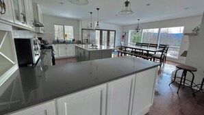 A spacious kitchen with a large island, white cabinetry, and pendant lighting.
