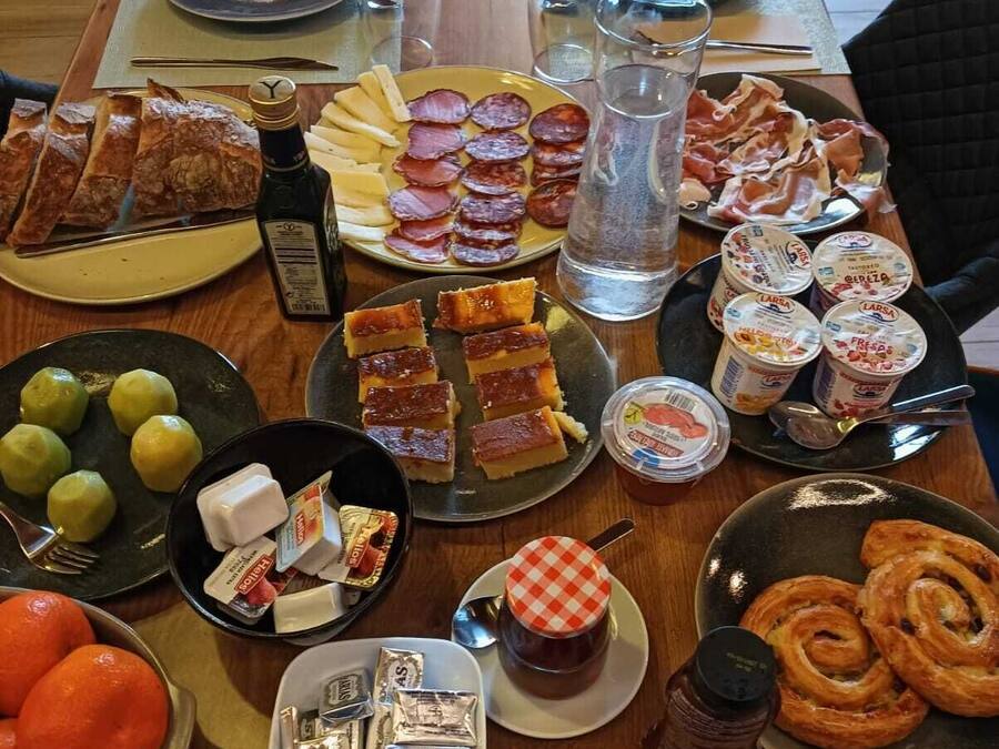A table set with various food items including bread, cheese, ham, and pastries.