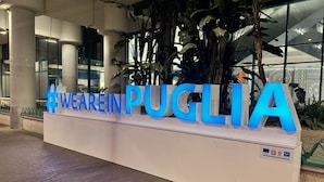 Ein Empfangstisch mit den Schriftzügen "WEAREIN PUGLIA" in großen blauen Buchstaben.