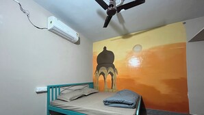 A single bed with a teal frame and grey bedding in a room with a herringbone-patterned floor. - Jungle by sturmfrei Jaipur (Jaipur)