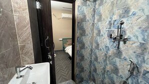A bathroom with a sink, shower, and a door leading to a bedroom. - Jungle by sturmfrei Jaipur (Jaipur)