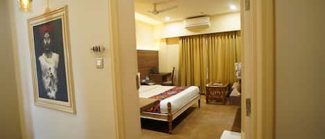 A hotel room with a bed, a desk, a chair, a nightstand, and a wall-mounted air conditioner.