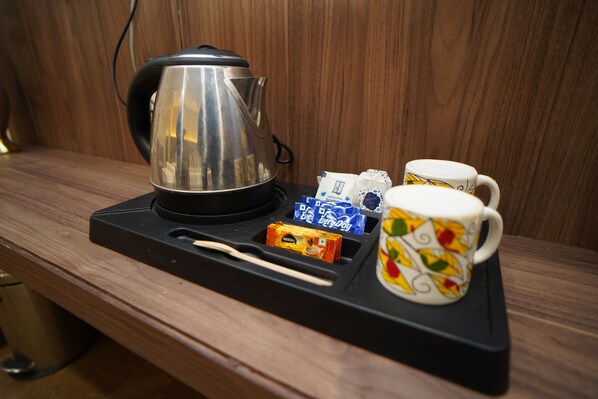 Una zona de cocina con hervidor, una bandeja con taza y aperitivos, y una encimera de madera.