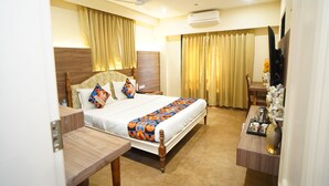 A hotel room with a bed, bedside table, and a desk with a chair. - Deotel Inn Pithampur by JMC (Dr. Ambedkar Nagar)