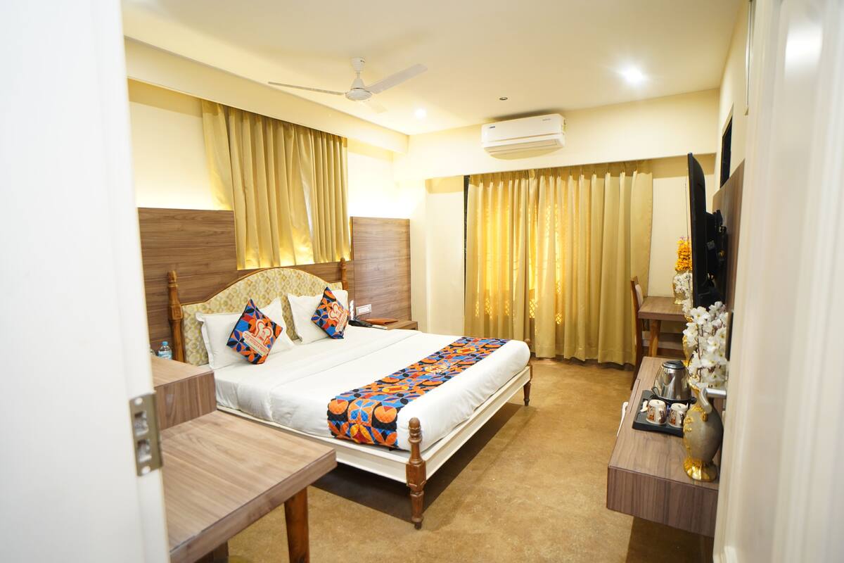 A hotel room with a bed, bedside table, and a desk with a chair.