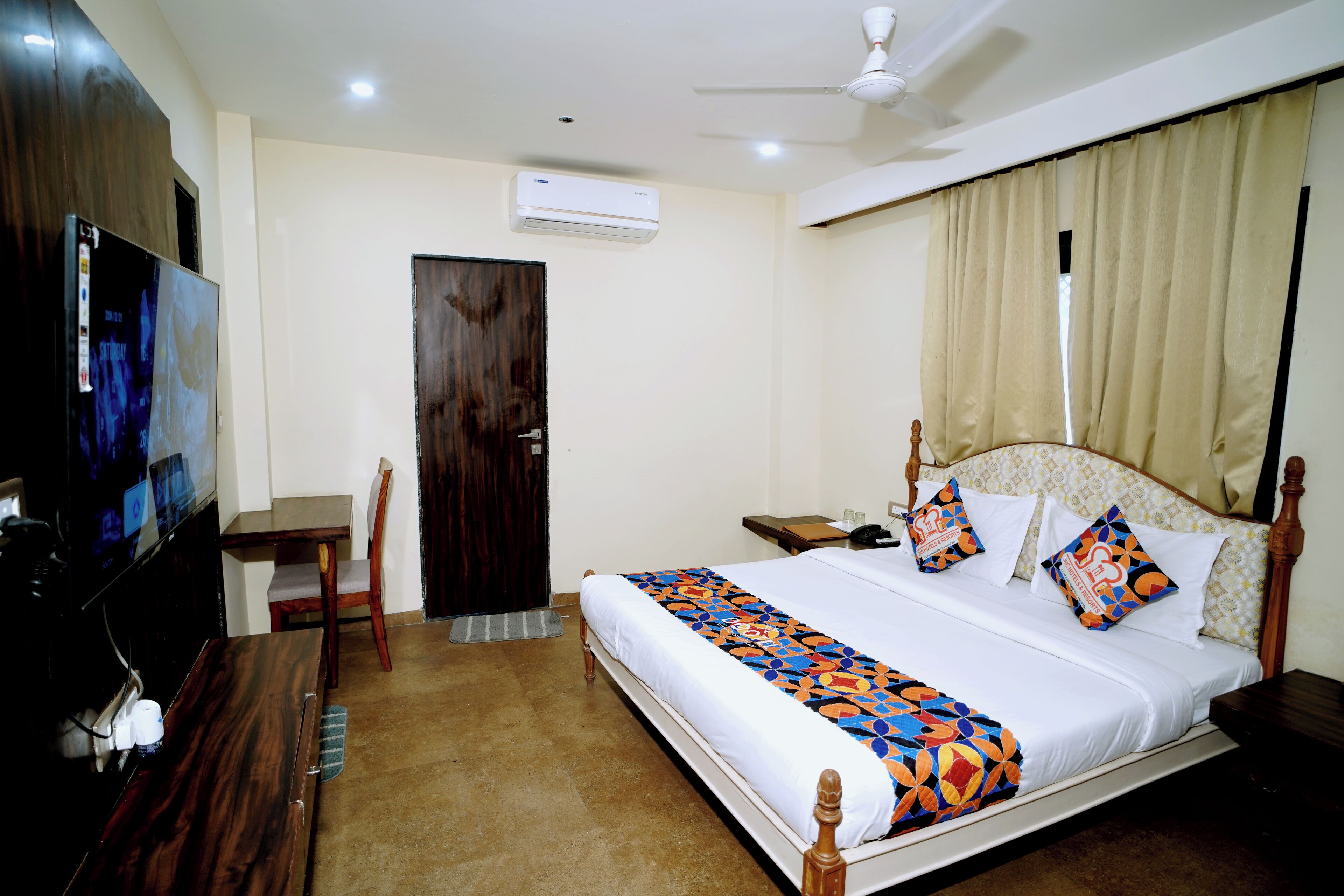 Une chambre d’hôtel équipée d’un lit, d’un bureau, d’une télévision et d’un appareil de climatisation.