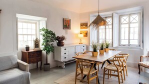 Et spiseområde med et træbord og stole, en lysekrone og krukker med planter.