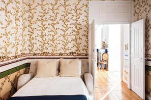Une chambre à coucher comprenant un lit, une chaise et une porte donnant sur une autre pièce.