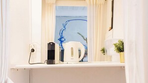 A compact bathroom with a white sink, a mirror above it, a small trash bin, and a white refrigerator. - Central Studio Suite - Ericeira (Ericeira)